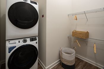 A white washing machine is stacked on top of another in a laundry room.